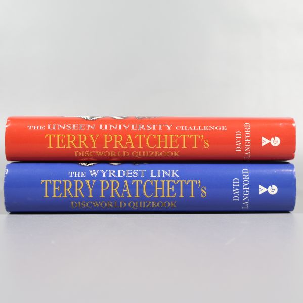 Böckernas ryggar, en röd och en blå, båda med guldtext och titlar