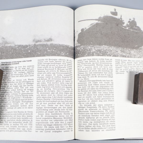 Uppslag ur boken med svartvit bild på stridsvagnar och text
