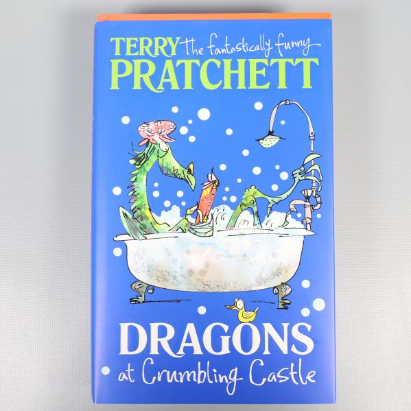 Framsida på Dragons at Crumbling Castle med blått omslag och illustration av drakar i badkar