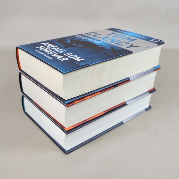 Tre Tom Clancy-böcker staplade, fokus på översta boken