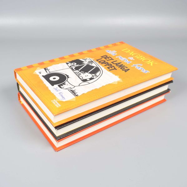 Närbild på bokstapeln med tydliga omslag och hörn i orange och svart