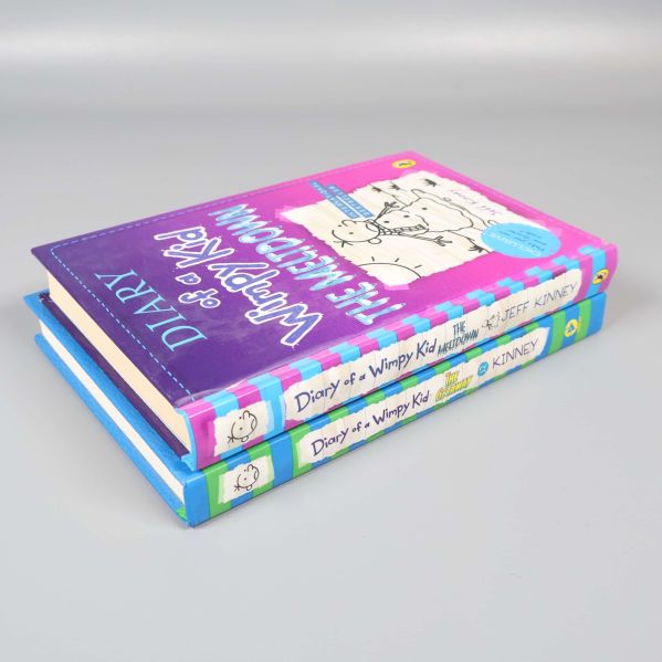 Sned vy av två staplade Diary of a Wimpy Kid-böcker på grå bakgrund