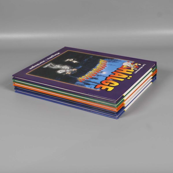 Fem staplade Hälge-album liggande på grått underlag