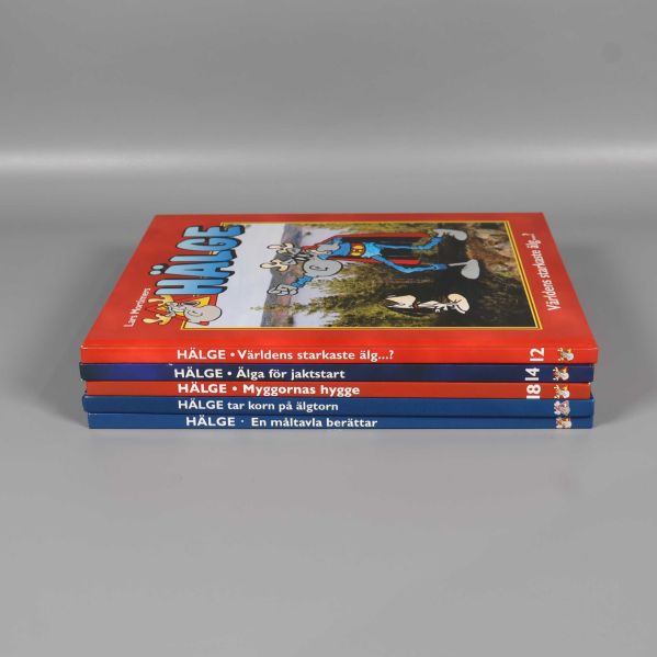 Hälge bokpaket liggande i stapel, boktitlar synliga på ryggarna