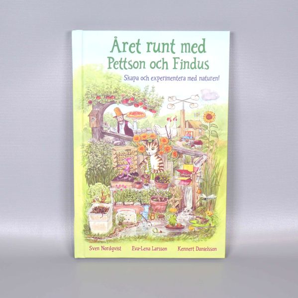 Omslaget till boken Året runt med Pettson och Findus med tecknade figurer och trädgårdsmiljö