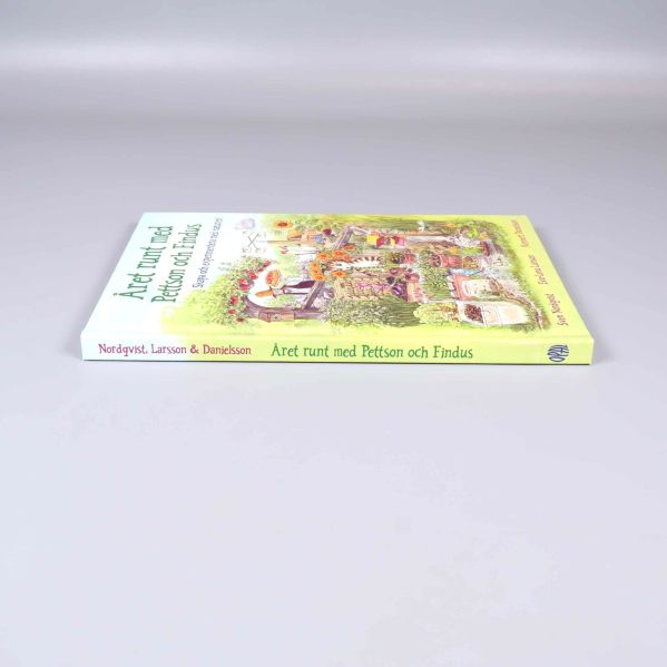 Boken Året runt med Pettson och Findus liggande på sidan, ryggen synlig