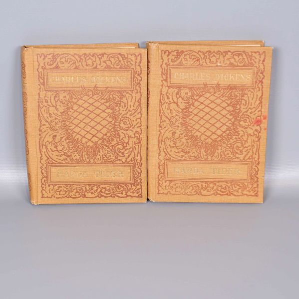 Två böcker Hårda tider av Charles Dickens med dekorativa gula omslag