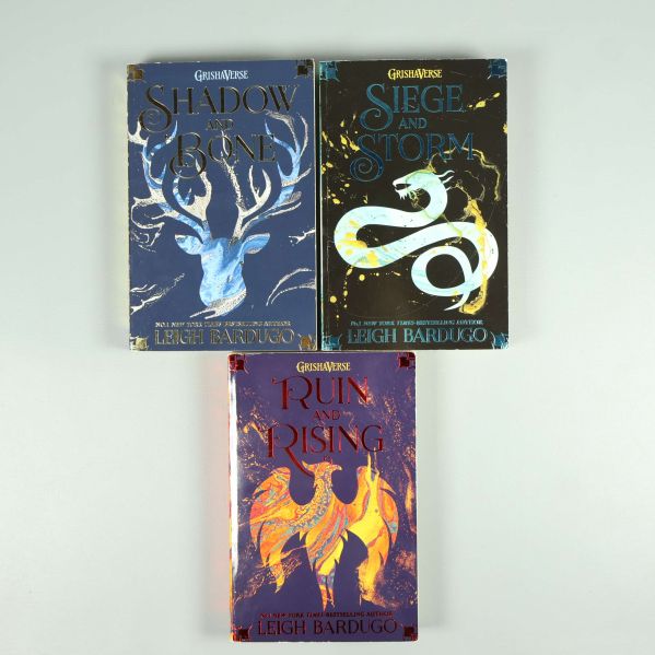 Tre böcker från Grishaverse trilogin utspridda: Shadow and Bone, Siege and Storm, Ruin and Rising