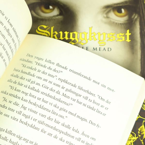 Uppslagen sida i bok med texten synlig och omslag i bakgrunden