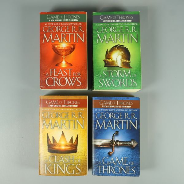 Fyra Game of Thrones böcker liggande med omslagen uppåt i olika färger