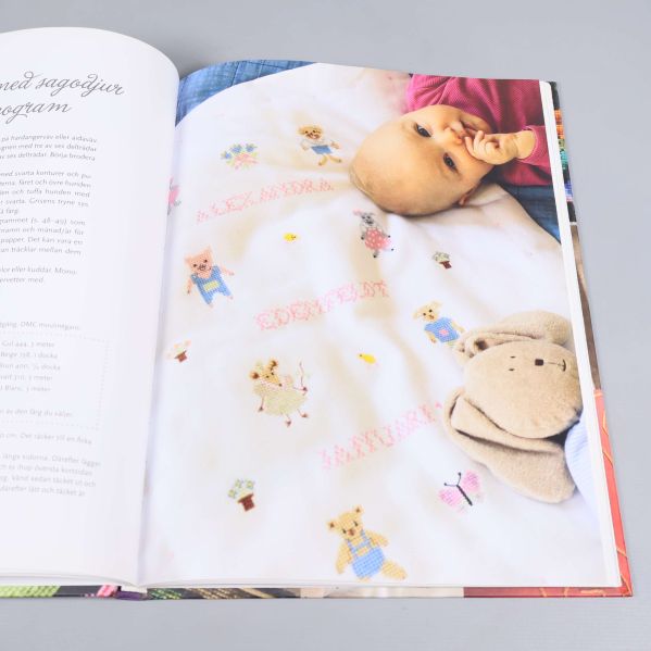 Innersida med bild på babyfilt broderad med djur och namn samt en baby