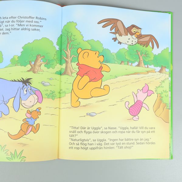 Uppslag med illustrationer på Nalle Puh, I-or, Nasse och Uggla, svensk text