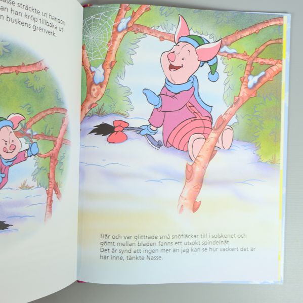 Uppslag ur Nalle Puh-bok med illustration av Nasse i snön och svensk text