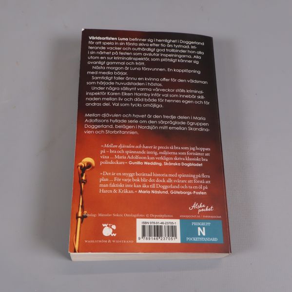 Baksida av pocketboken Mellan djävulen och havet med beskrivning och ISBN