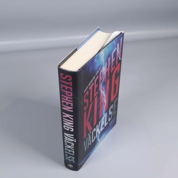 Väckelse av Stephen King i vinkel, ryggen och omslaget synliga