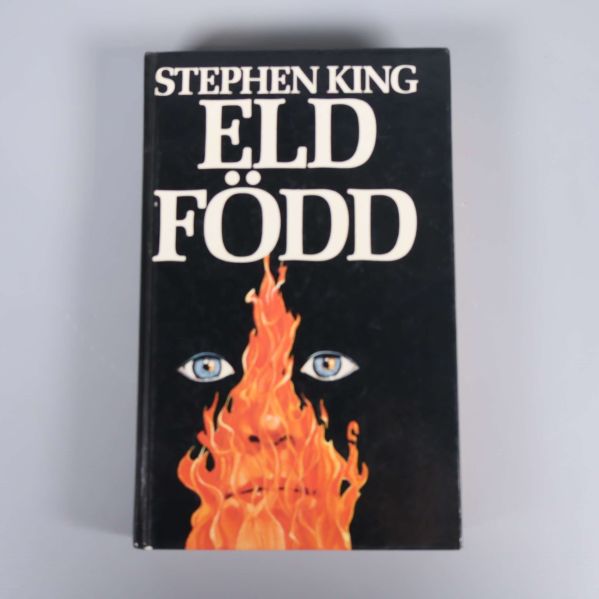 Framsida på boken Eld född av Stephen King med svart bakgrund, eldflammor och två blå ögon