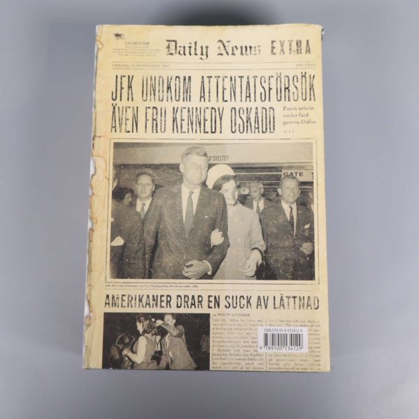 Baksida av boken 22/11 1963 med JFK och historiska tidningsurklipp, barcode synlig