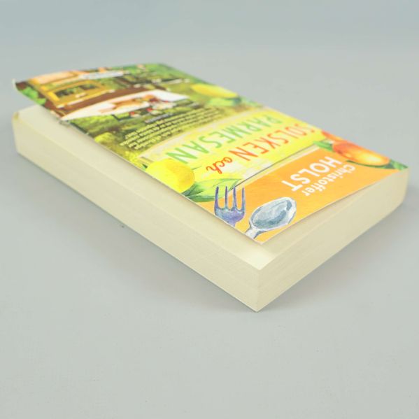 Boken Solsken och parmesan liggande, visar bokpärmens och sidornas tjocklek
