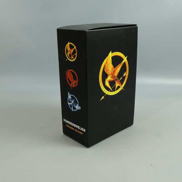 Svart bokbox med Hungerspelen-symboler i färg och Suzanne Collins namn