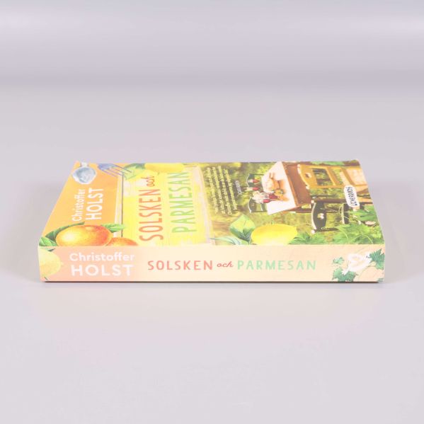 Pocketboken Solsken och parmesan liggande, visar rygg och omslag