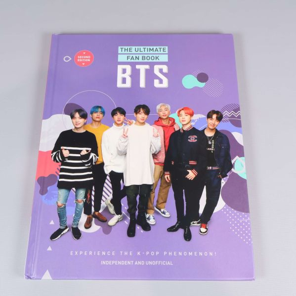 Framsida av boken BTS The Ultimate Fan Book med gruppen BTS i färgglada kläder på lila bakgrund
