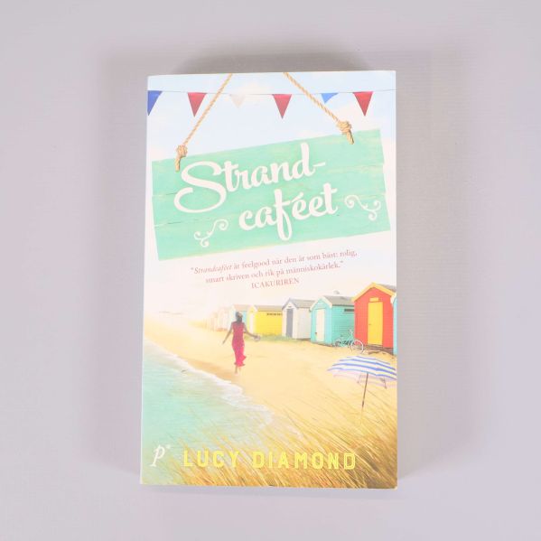 Framsidan av boken Strandcaféet med strandmotiv och färgglada strandhus