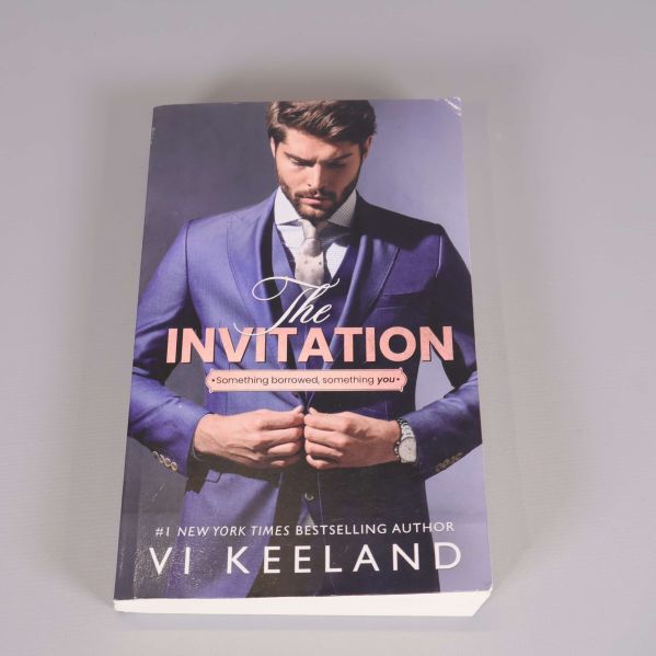 Omslag till The Invitation av Vi Keeland med elegant kostymklädd person