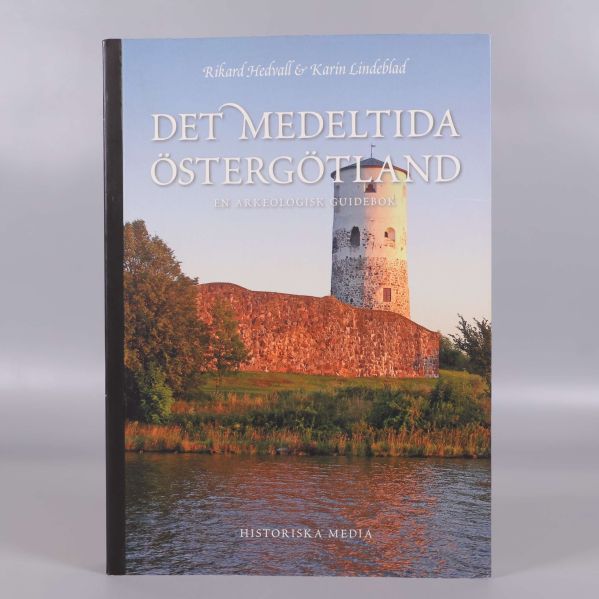 Framsidan av boken Det medeltida Östergötland med borg i solnedgång