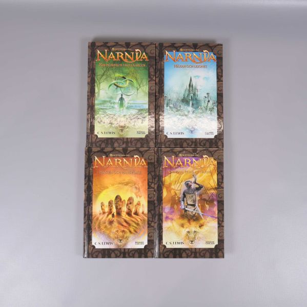 Fyra böcker i Narnia-serien med illustrerade omslag, liggande i två rader