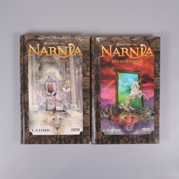 Två inbundna böcker ur serien Berättelsen om Narnia med illustrerade omslag
