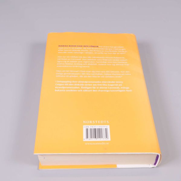 Baksida av boken Soluppgång över strandpromenaden med text och ISBN