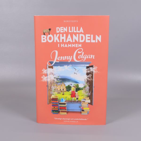 Framsidan av boken Den lilla bokhandeln i hamnen med illustrerat fönster och böcker