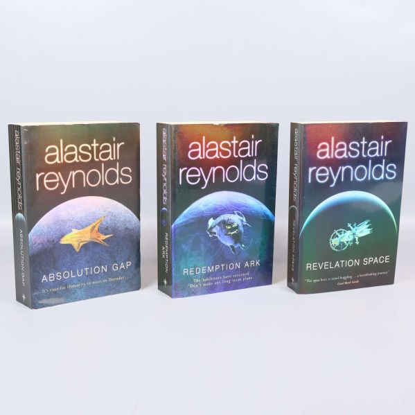 Tre stående böcker av Alastair Reynolds med färgstarka omslag