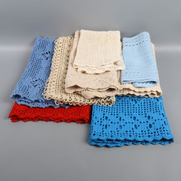 Fem virkade dukar i olika färger staplade