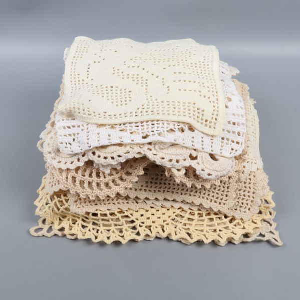 Stapel av virkade dukar i beige och naturvit