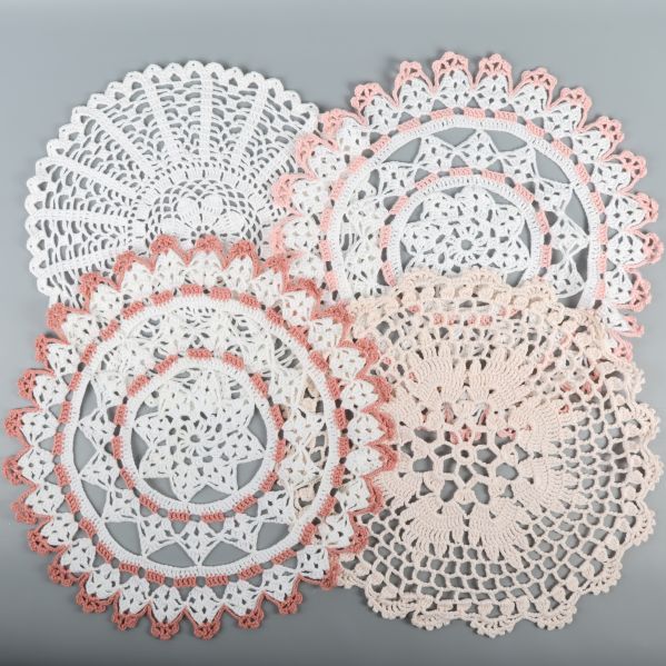 Fyra vita och rosa virkade dukar