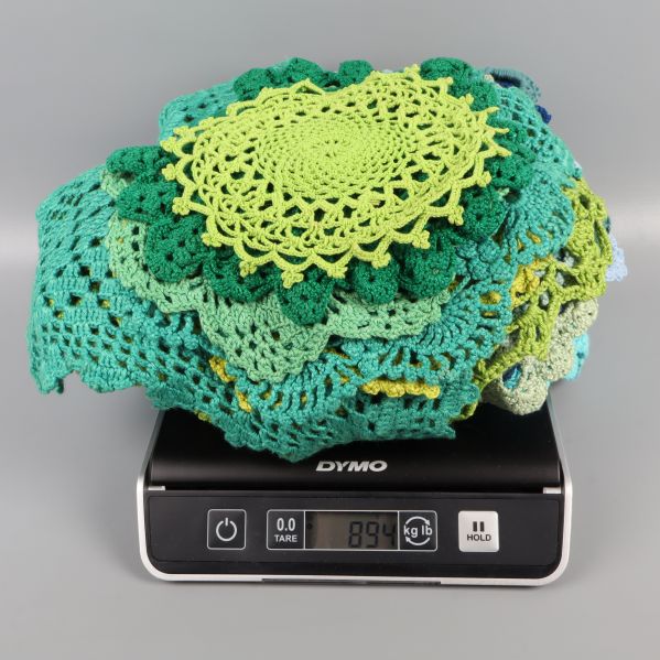 Virkat duk set placerat på våg, visar 894 gram