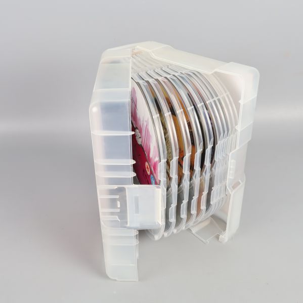 Öppen plastbox med flera DVD-skivor staplade på rad