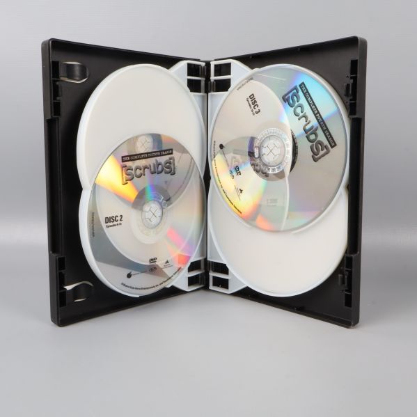 Öppnat DVD-fodral visar flera Scrubs-skivor inuti