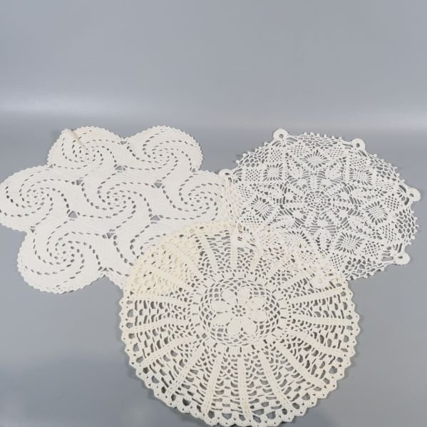 Tre ljusa virkade dukar i geometriska och runda mönster