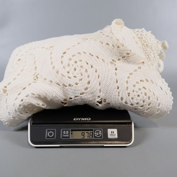 Virkad duk på våg som visar vikten 978 gram