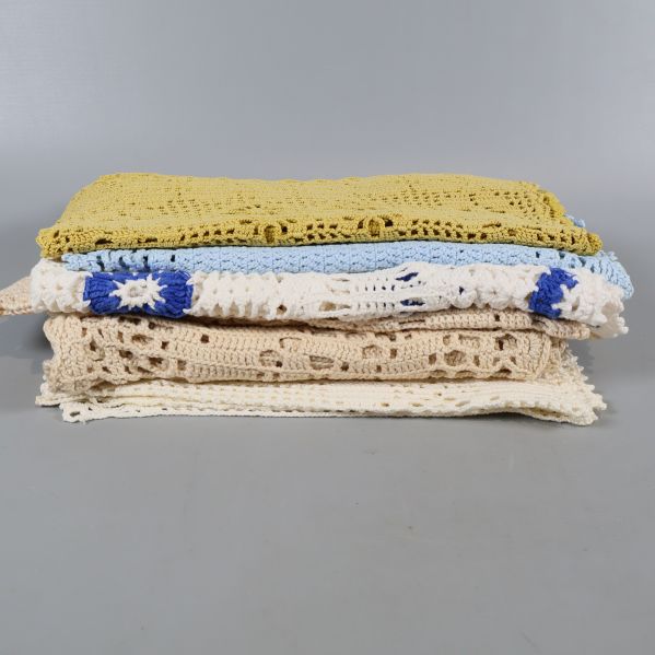 Flera vikta virkade dukar staplade på varandra i olika färger