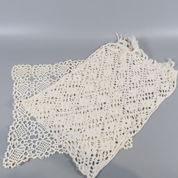 Två virkade dukar i ljust beige och vitt på rad