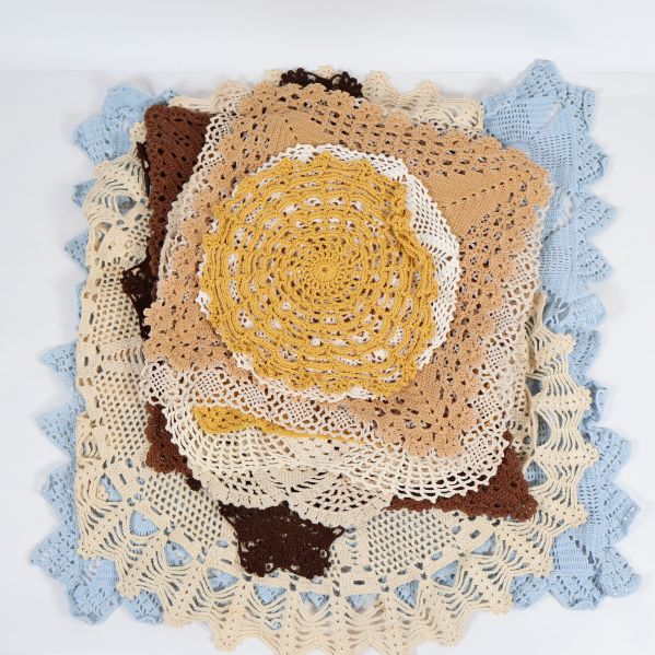 Hög med virkade dukar i olika färger och former