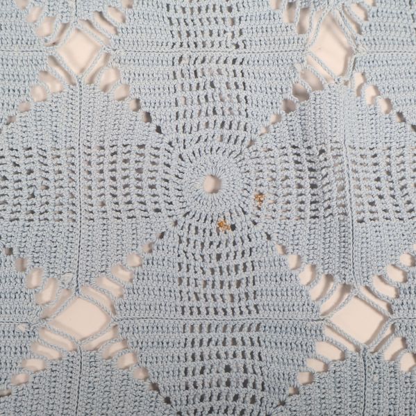 Närbild på ljusblå virkad duk med detaljerat mönster