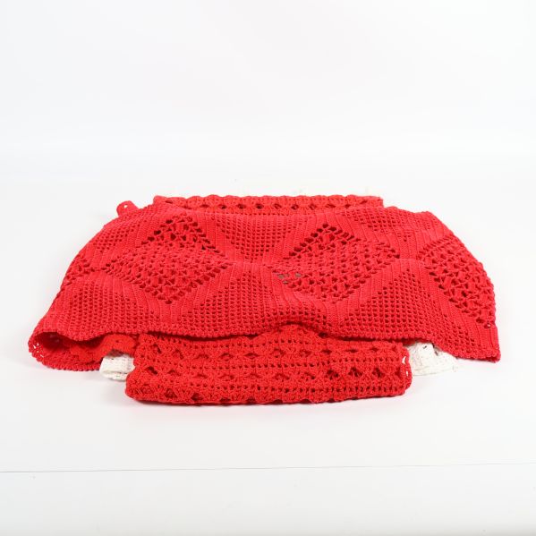 Virkade dukar i rött med dekorativa mönster staplade