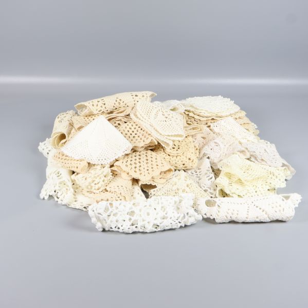 Stapel med virkade spetsdukar i olika nyanser på grå bakgrund