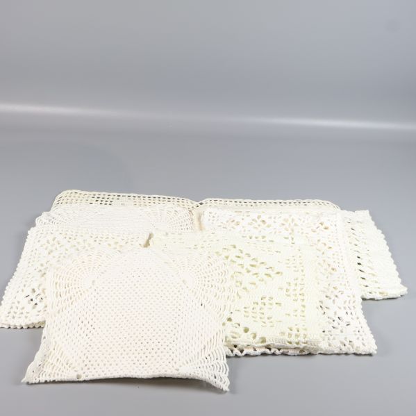 Utspridda virkade dukar i olika former mot grå bakgrund