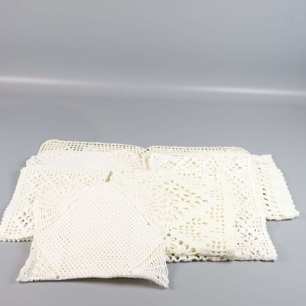 Uppfällda fyrkantiga gräddvita virkade dukar i olika storlekar
