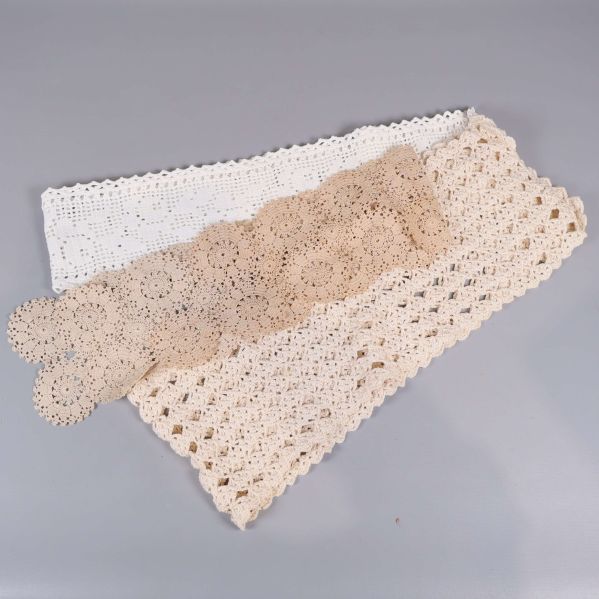 Långa virkade spetsar i beige och vitt sida vid sida